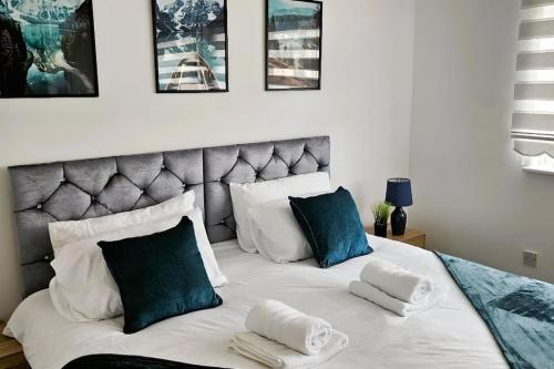 um quarto com uma grande cama branca com almofadas azuis em 4 Bedroom Spacious Entire House Sleeps 6 em Great Parndon