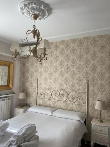 a bedroom with a white bed and a chandelier at Suite Comares in Granada