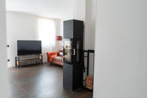 a living room with a television and a black refrigerator at Tra monte e lago in Terlago