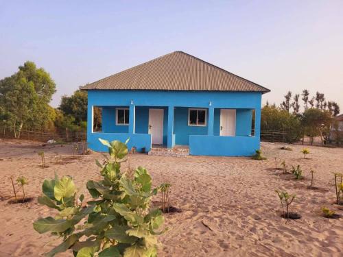 une maison bleue au milieu d'un champ dans l'établissement Jusula Beach Resort, à Sanyang