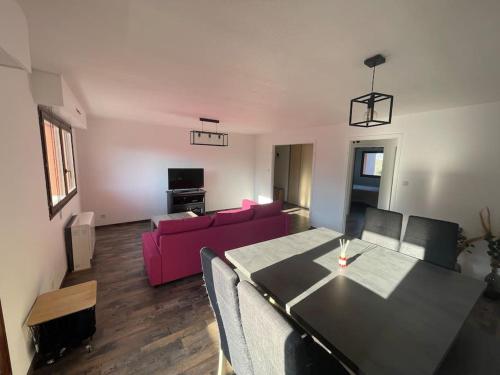 un soggiorno con tavolo e divano rosa di Appartement proche de Strasbourg a Illkirch-Graffenstaden
