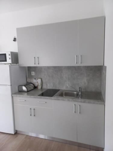 a white kitchen with a sink and a refrigerator at lastva 1&2 in Sveti Filip i Jakov