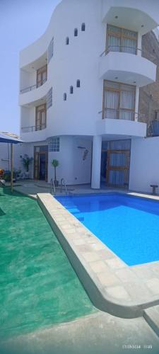 a large swimming pool in front of a building at El Capricho II Paracas in Paracas