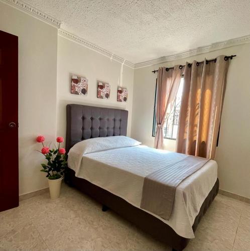a bedroom with a bed and a window with roses at Apartamento para máximo 3 personas, habitación privada con cama doble , dos sofá cama, comodo, bonito, central, bien ubicado, en el centro de palmira in Palmira