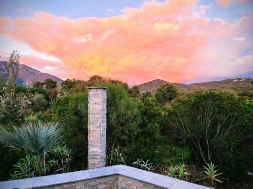 une cheminée en briques avec un coucher de soleil dans les montagnes dans l'établissement charmante petite maison au calme, à Eccica-Suarella
