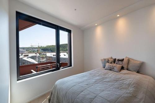 a bedroom with a bed and a large window at New waterfront apartment - Oslo city centre in Oslo