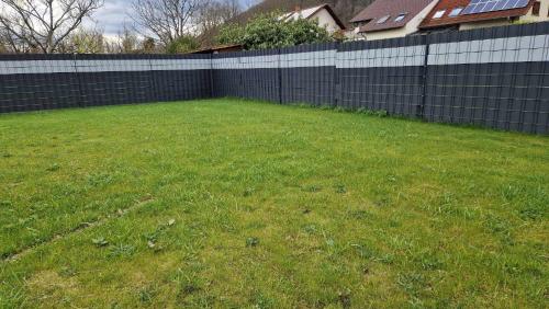 a backyard with a fence and a green yard at Ferienhaus Guldner mit Terrasse, Garten und Sauna in Überherrn