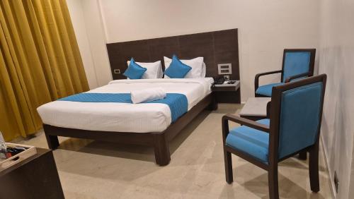a bedroom with a large bed and a blue chair at Hotel JANAS in Tirupati
