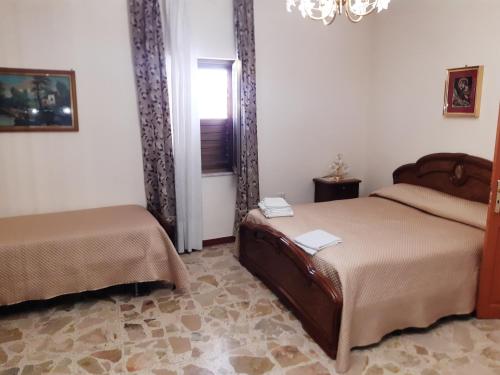 1 Schlafzimmer mit 2 Betten, einem Fenster und einem Kronleuchter in der Unterkunft La casa di Lina in Milena