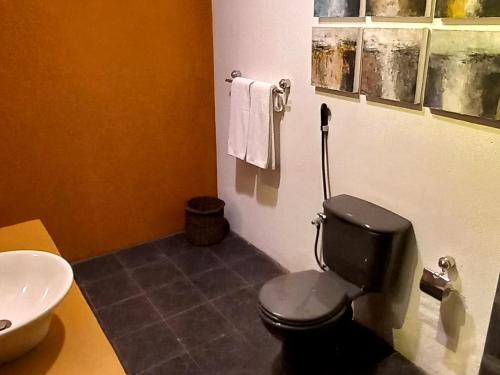 a bathroom with a black toilet and a sink at LUMBINI home stay in Colombo