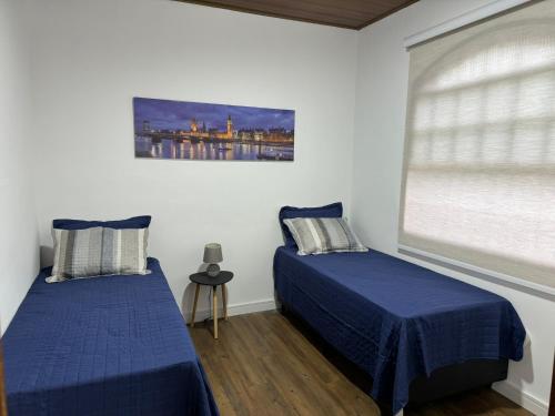 a bedroom with two beds and a window at Casa Inteira em Nova Friburgo - Moda Íntima in Nova Friburgo