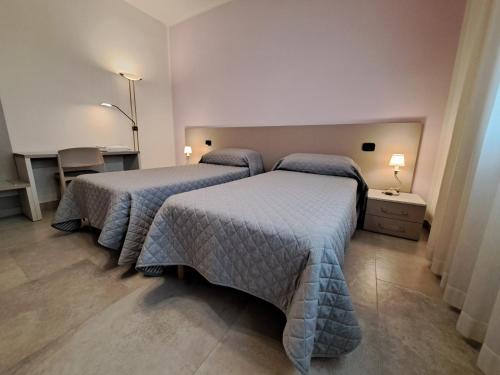 two beds in a room with two tables and two lamps at Borgo Barucchella in SantʼAndrà