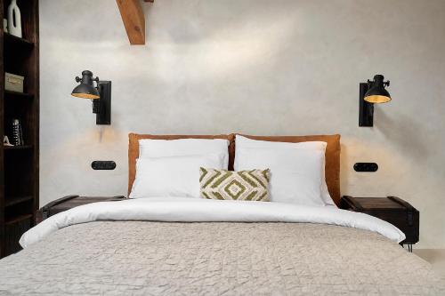 a bedroom with a bed with white pillows and two lights at Loft 16 in Iława
