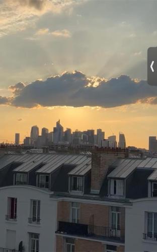 a view of a city skyline with roofs of houses at Étage d’un duplex au 17ème arr de Paris , vue sur le Défense, à 10min des champs Élysée in Paris