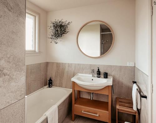 a bathroom with a sink and a tub and a mirror at Beachfront Retreat On Revell in Hokitika