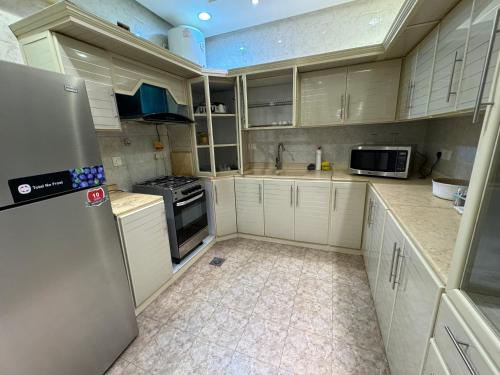 una cucina con mobili bianchi e un frigorifero di شقة فاخرة غرفتين وصالة النرجس ١٥ a Riyad