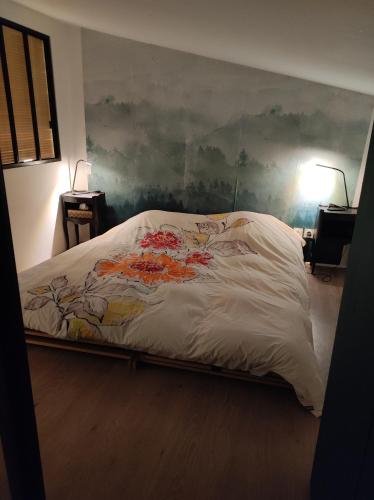 a bed in a bedroom with a painting on the wall at Logement cosy Sous Les Toits in Charmes-sur-Rhône