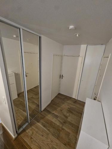 une pièce vide avec des portes coulissantes en verre et du parquet dans l'établissement Cosy Furnished Studio Near Paris and Stade de France, à Saint-Ouen