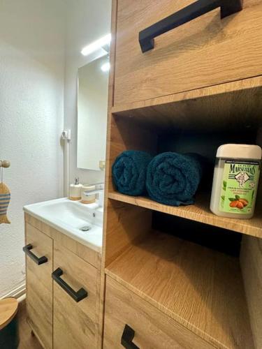 La salle de bains est pourvue d'un lavabo et de serviettes bleues. dans l'établissement *La Brise Marine*Piscine*Parking*Clim*, au Grau-du-Roi