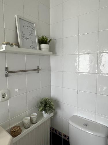 Baño de azulejos blancos con aseo y plantas en Preciosa casa con piscina de agua salada y aire acondicionado, en Llançà