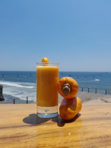 um copo de sumo de laranja sentado numa mesa perto da praia em Kuluka Resort And Spa em San Miguel