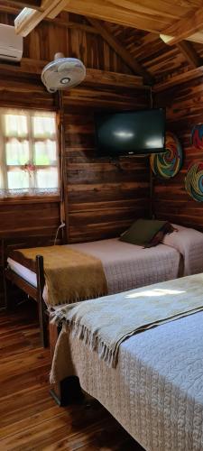 a bedroom with two beds and a flat screen tv at Congos Hostal y Camping in Playa Hermosa