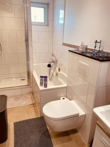 a white bathroom with a toilet and a bath tub at Wunderschöne Wohnung nähe Essen / Düsseldorf in Heiligenhaus