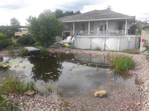 une maison avec un étang devant une maison dans l'établissement Notre nid d'amour - jacuzzi, piscine, billard, bar extérieur, terrain de boules, à Saint-Sernin-du-Bois