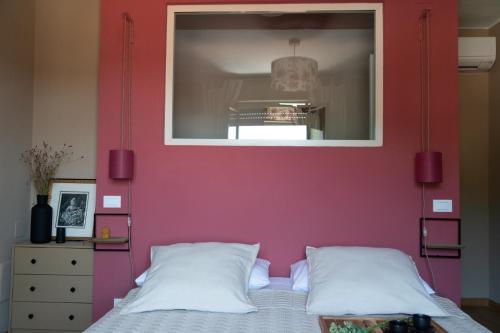 a bedroom with a red wall and a bed with two pillows at La Bastia - Bed & Soul in Nuvolento