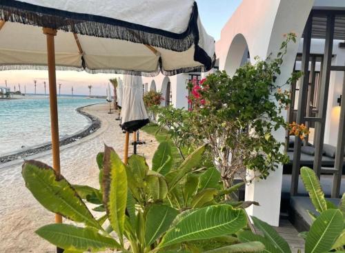 una playa con sombrilla y algunas plantas en Le Sidi Cabana ( hacienda bay ), en El Alamein