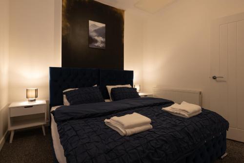 a bedroom with a blue bed with two towels on it at The Orange County in Stoke on Trent