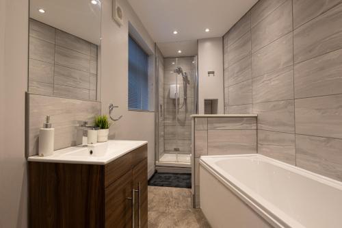 a bathroom with a tub and a sink and a bath tub at The Orange County in Stoke on Trent