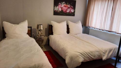 een slaapkamer met 2 bedden met witte lakens en een raam bij Niehler Hotel in Keulen