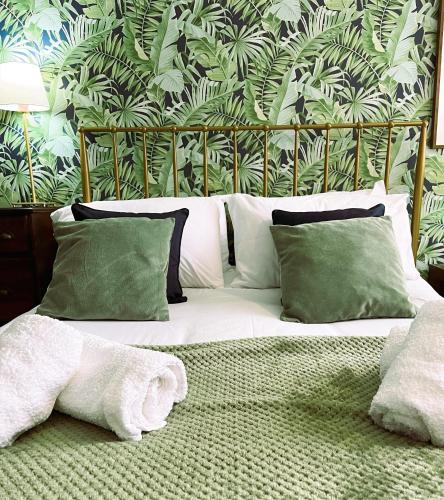 a bedroom with a bed with green and white pillows at COLE HOUSE in Solihull