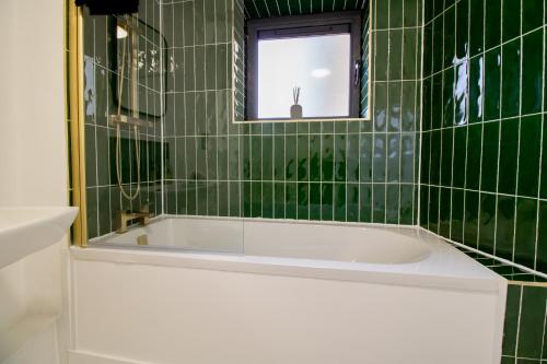 een groen betegelde badkamer met een bad en een raam bij Newcastle City Apartments - FREE Parking Baltic Quay in Gateshead