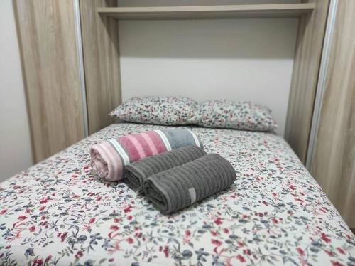 un letto con due coperte e cuscini sopra di Apartamento inteiro no Bairro Alto Umuarama a Uberlândia