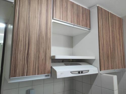 a white stove in a kitchen with wooden cabinets at Apartamento inteiro no Bairro Alto Umuarama in Uberlândia