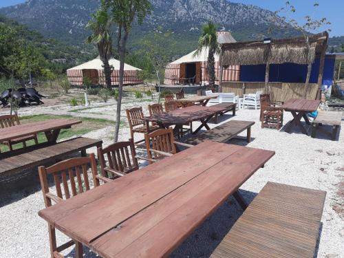 a group of picnic tables and chairs with mountains in the background at Adrasan Yıldız Bungalow Tatil Köyü in Adrasan