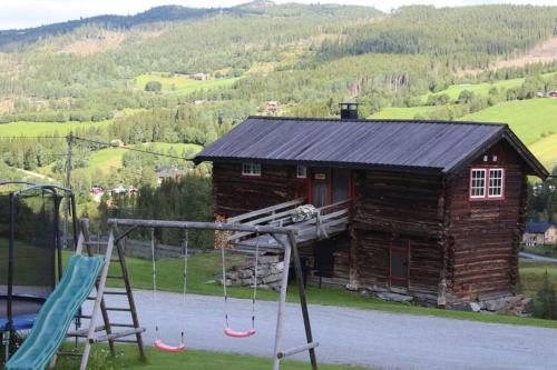 une aire de jeux avec balançoires et une cabane en rondins dans l'établissement Trevet by Norgesbooking - cabin close to skicenter, à Holo