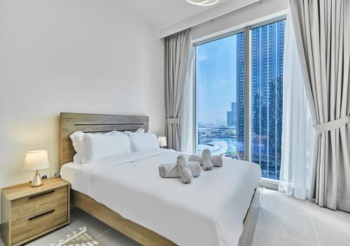 ein Schlafzimmer mit einem großen weißen Bett und einem großen Fenster in der Unterkunft Majestic Forte2 17th- Burj khalifa & Fountain view in Dubai