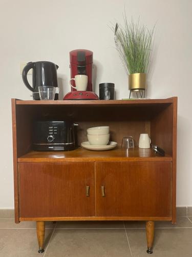 a wooden cabinet with a coffee maker and dishes on it at La Canopée des Arbres, Anna in Ellezelles