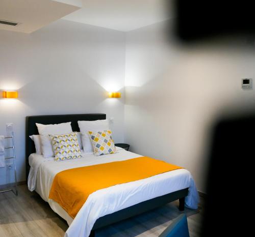 een slaapkamer met een bed met een oranje deken en kussens bij LE CENTRAL HOTEL BAR RESTAURANT in Balaruc-les-Bains