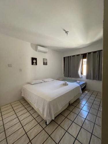 um quarto com uma cama branca e piso em azulejo em Pousada Aconchegante - Suíte em Jequié