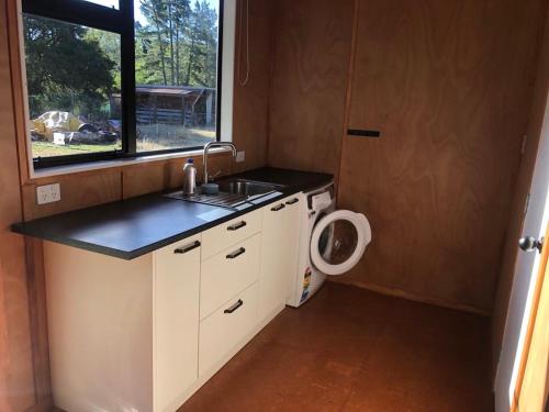 uma pequena cozinha com um lavatório e um WC em The River Shack em Nelson
