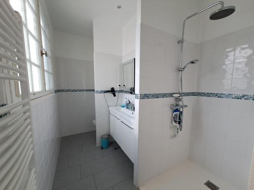 une salle de bain blanche avec une douche et un lavabo dans l'établissement Villa Blanche spacieuse pour 8 (modulable), avec mer, piscine, balades à vélo, à La Tremblade
