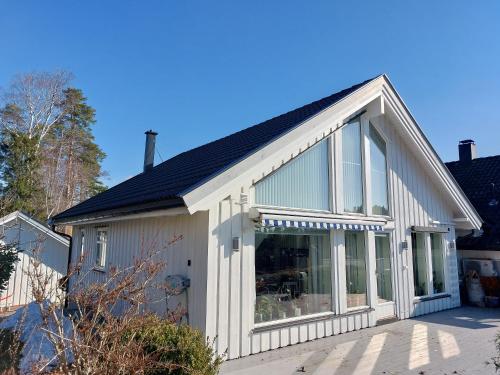 a house with large glass windows on the side of it at Flaskebekk at Nesodden with unbeatable Oslo Fjord views and a private beach hut in Nesoddtangen