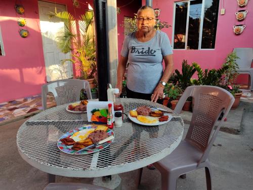 un hombre de pie junto a una mesa con comida en ella en Guest House Nena, en Moyogalpa