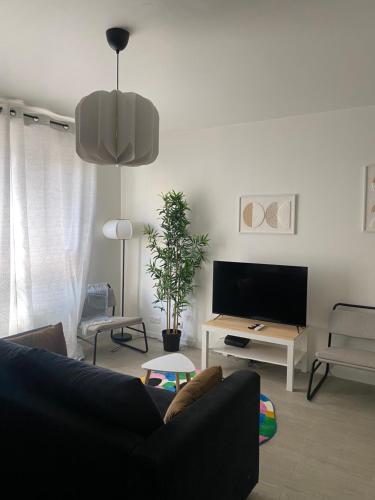 un salon avec un canapé et une télévision à écran plat dans l'établissement Aux Portes de Paris - Parc légion d’honneur, à Saint-Denis