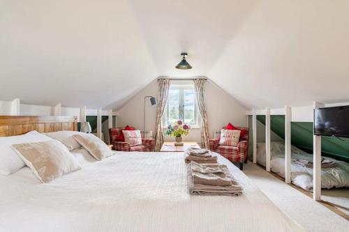 a bedroom with a large white bed and chairs at Suffolk Fieldview Country Cottage in Toft Monks