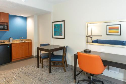 a room with a desk and a table and chairs at Holiday Inn Express Hotel & Suites Jacksonville Airport by IHG in Jacksonville